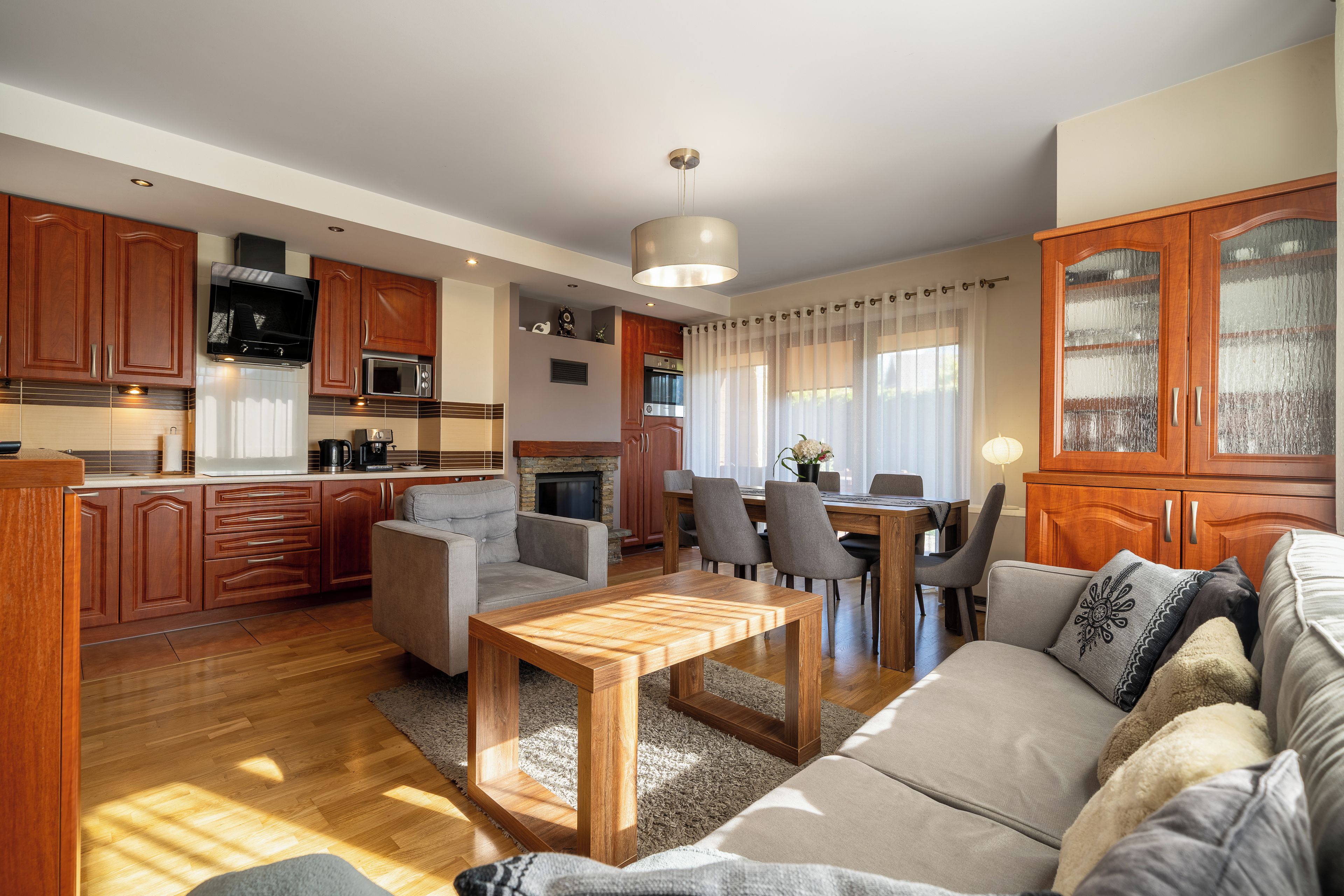 Una sala de estar moderna con un sofá, una mesa de centro de madera y un comedor con sillas.