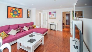 A modern living room with a pink sofa, white coffee table, and a flat-screen TV. - El pentagrama de Cadiz (Cádiz)