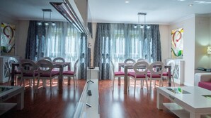 A modern dining area with white tables and chairs, large windows with sheer curtains, and abstract artwork on the walls. - El pentagrama de Cadiz (Cádiz)