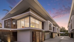 A modern two-story house with large windows, a flat roof, and a garage.