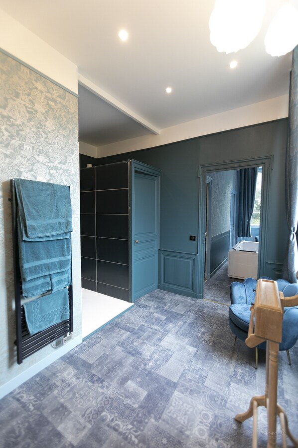 Une salle de bain moderne équipée d’une douche, d’un porte-serviettes et d’un espace coiffeuse.