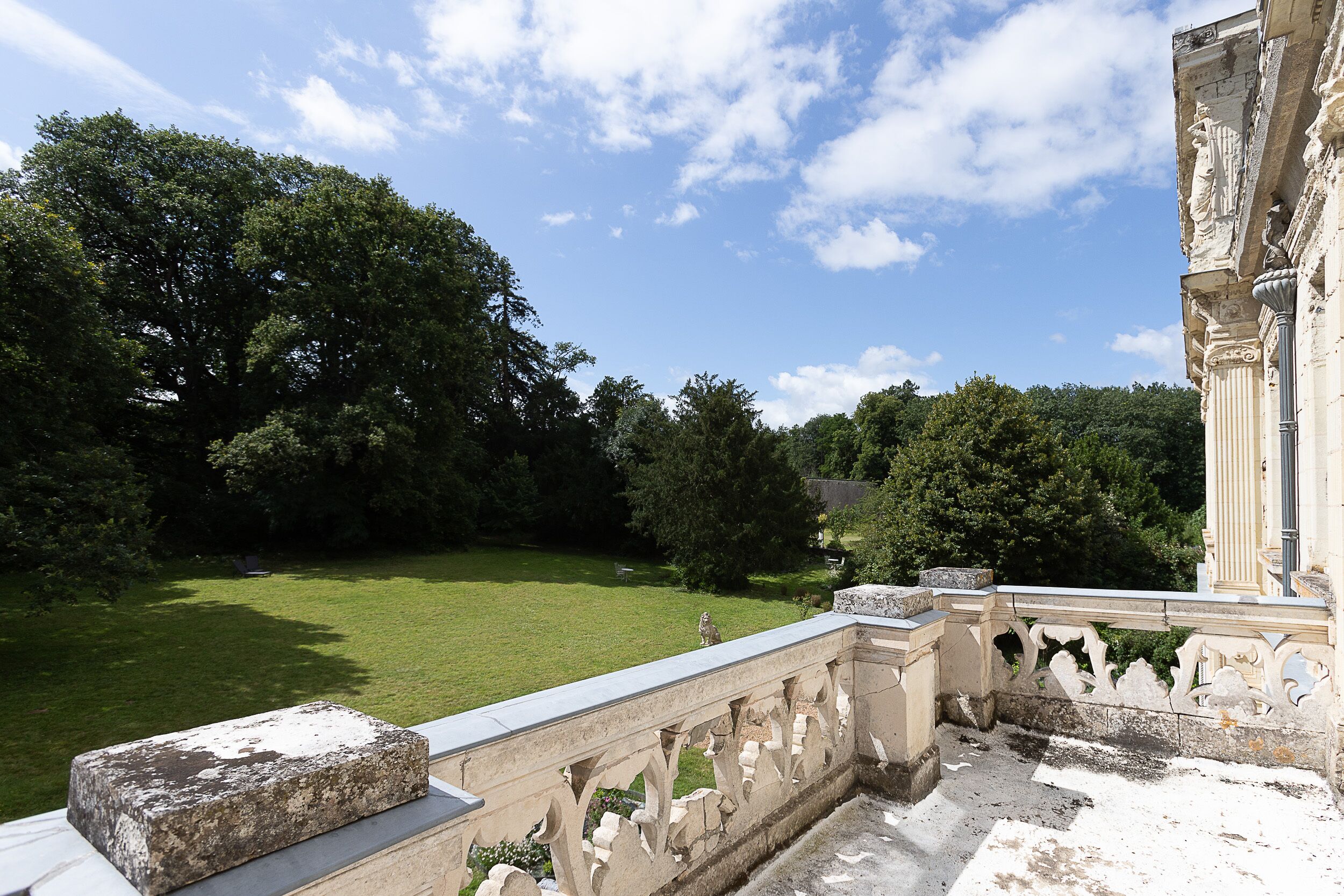 A stone balustrade overlooking a well-manicured lawn with trees and a classical building in the background.