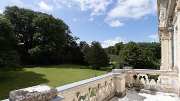 A stone balustrade overlooking a well-manicured lawn with trees and a classical building in the background.