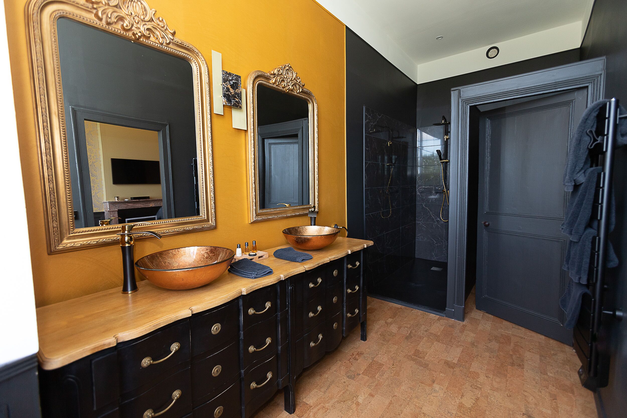 A bathroom with two large mirrors, a copper sink, and a dark door.