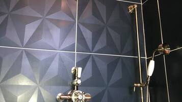 Een badkamer met een wand met een geometrisch patroon, een douchekop en een handdouche.