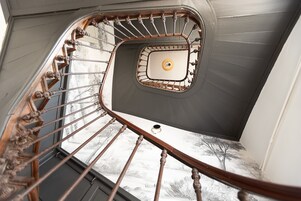 Escadaria em espiral com guarda-corpo de metal e luminária central.