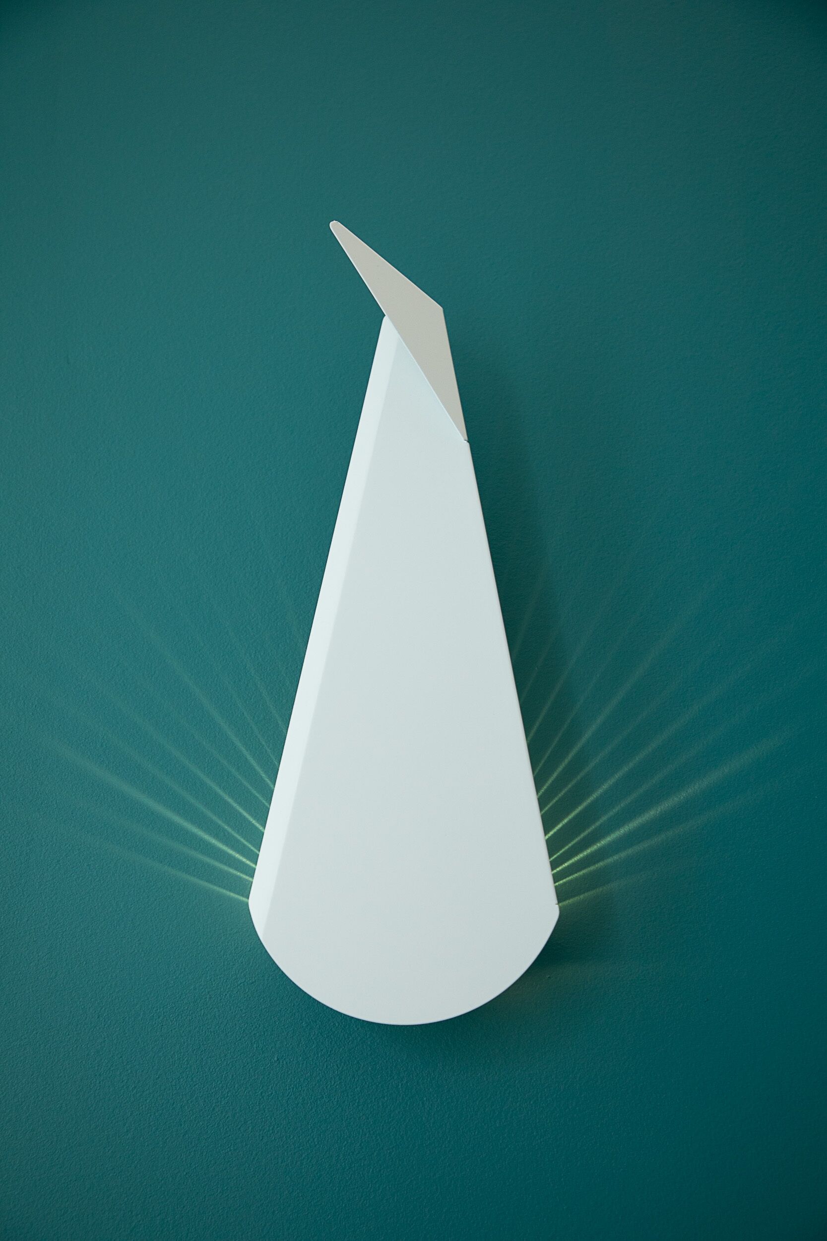 A white conical object with a pointed tip, set against a teal background.