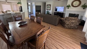 Un grand espace de vie comprenant une table à manger, des chaises, un canapé et un téléviseur.