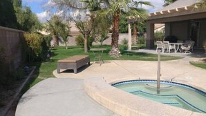 Un jardin avec une piscine, une table de patio et des sièges d’extérieur.