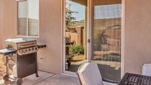 A patio with a grill, a sliding glass door, and a view of a backyard. - Rock Canyon Oasis 4 Bedroom Home by RedAwning (Washington)