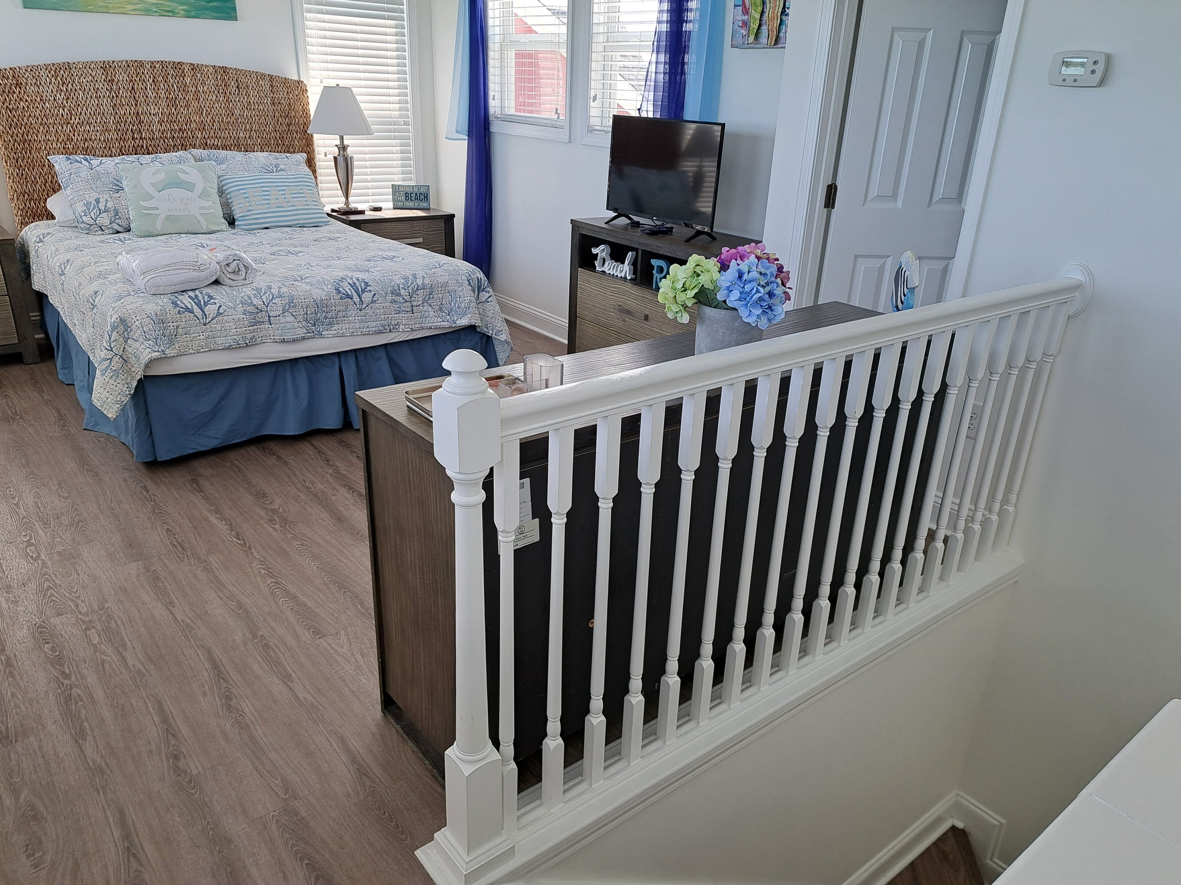 A bedroom with a bed, nightstand, TV, and a view of the outside.