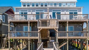 A multi-story wooden deck with a staircase leading to the upper levels, surrounded by a residential building.