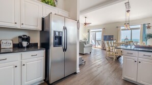 A modern kitchen with white cabinetry, a stainless steel refrigerator, and a coffee maker.