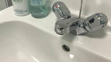 Ein Waschbecken mit zwei Lotionflaschen und einem Chrom-Wasserhahn.