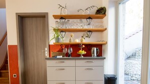Una cucina con un armadietto in legno, una pianta e una finestra che si affaccia su un muro di pietra e delle scale.