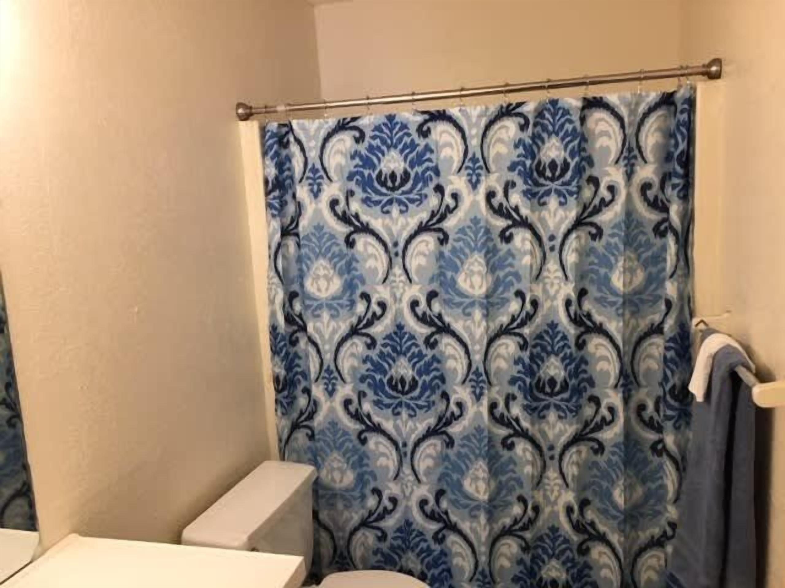 Ein Badezimmer mit einem waschbärmuster-Duschvorhang, einer Toilette und einem Handtuchhalter.