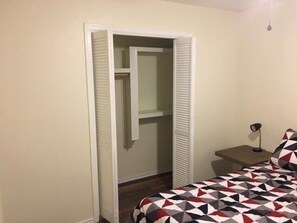 Un dormitorio con una cama, una mesita de noche, una lámpara y un armario.