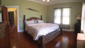 Une chambre à coucher avec un lit en bois, une table de chevet, une lampe et une fenêtre avec des rideaux.