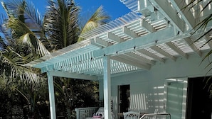 A swimming pool with a pergola, lounge chairs, and a covered seating area.