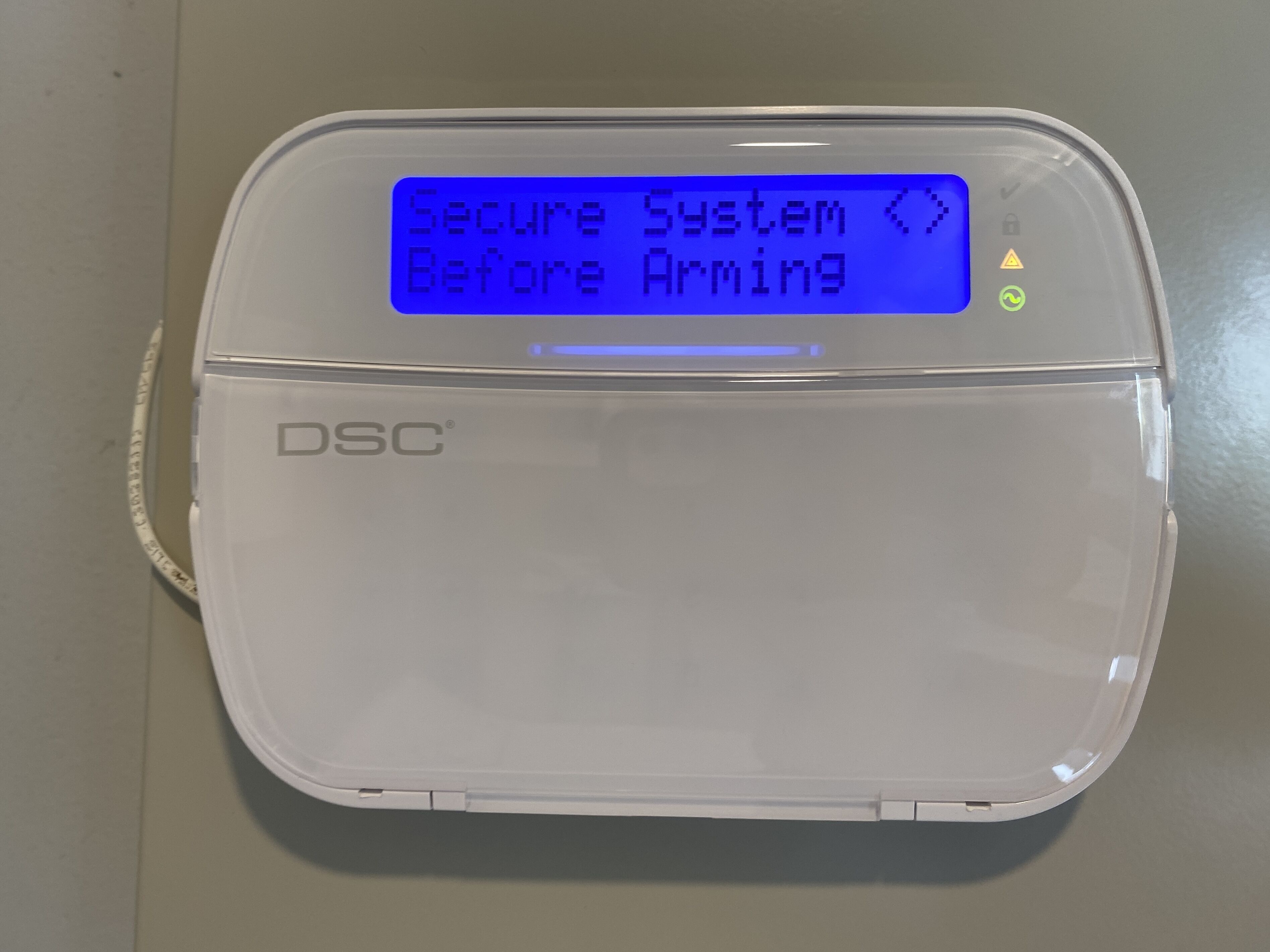 A DSC security system device with a blue screen displaying "Secure System Before Arming".