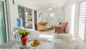 A bright, sunlit room with a glass table, wicker furniture, and a water dispenser.