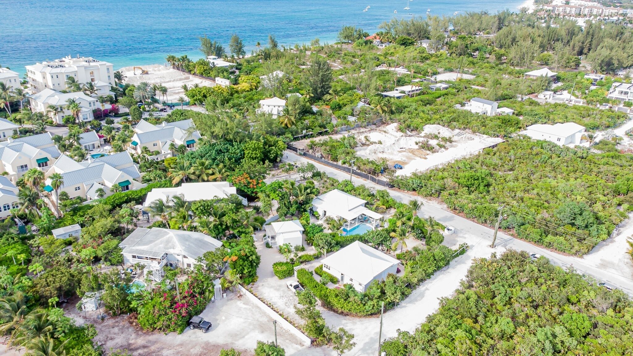 Vista aérea de una zona residencial con casas, una carretera y una playa al fondo.