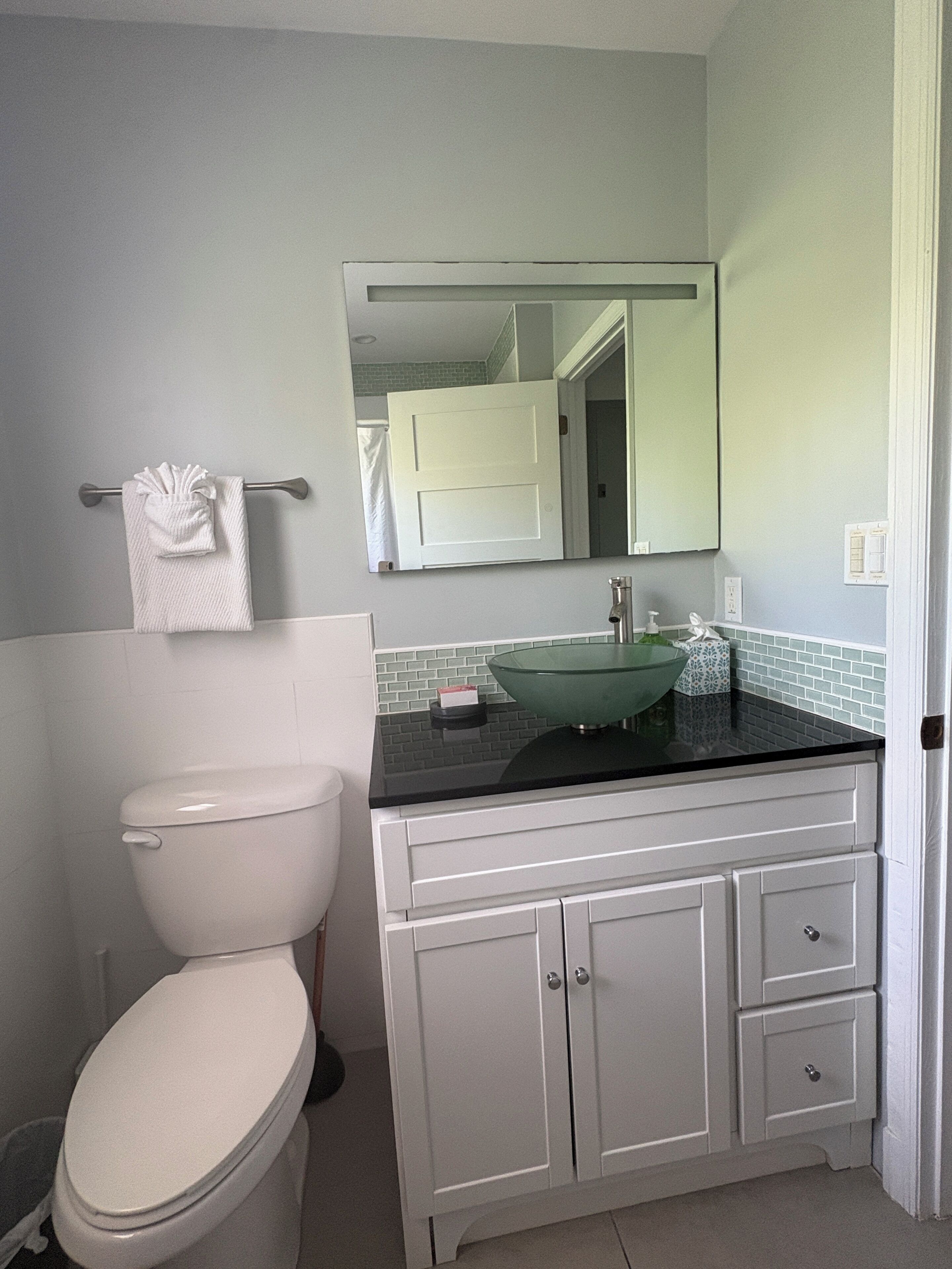 A bathroom with a toilet, a sink with a mirror above it, and a towel rack.