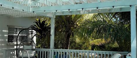 Un área de piscina con una pérgola blanca, sillas de descanso y una hamaca colgante.