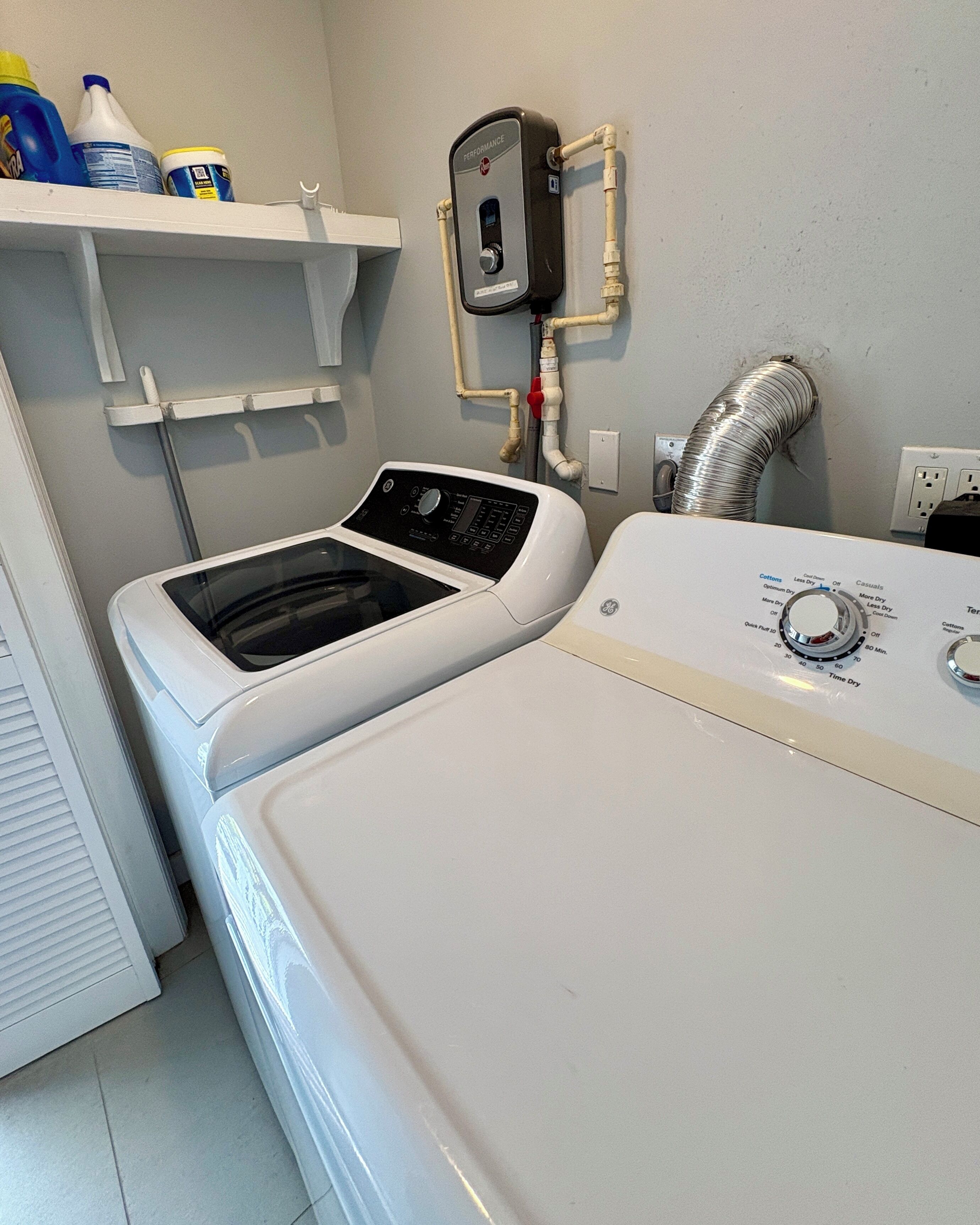 Et vaskerum med to vaskemaskiner, en varmtvandsbeholder og en ventilationsrør.
