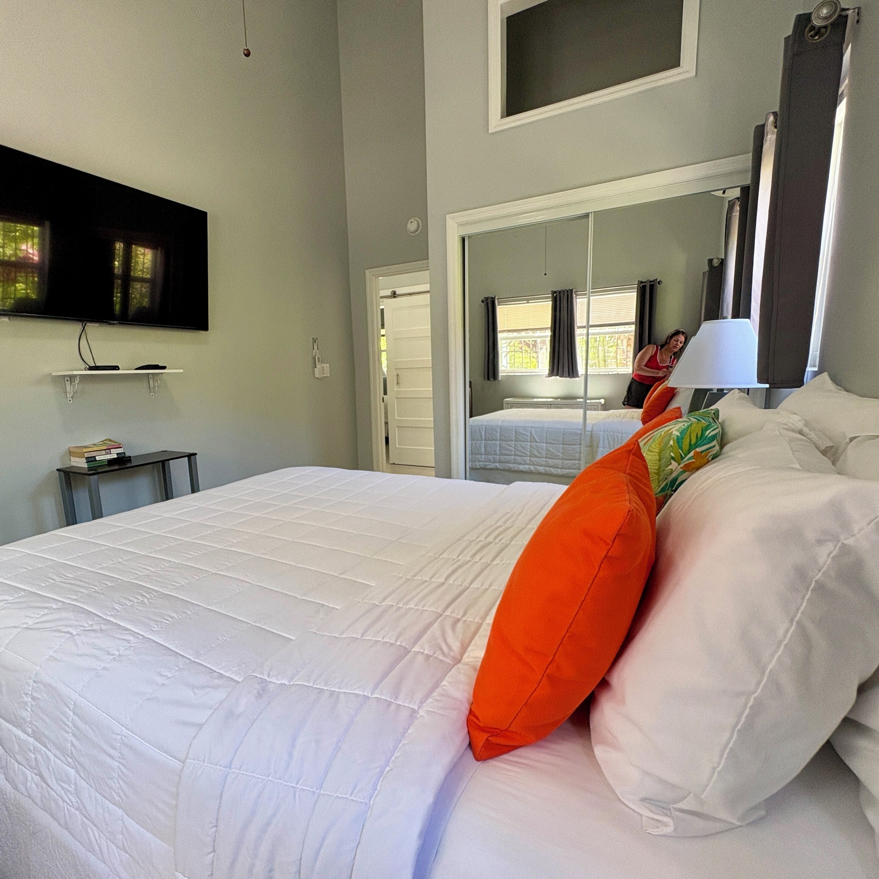 Una habitación de hotel con una cama, televisión, espejo y ventana.