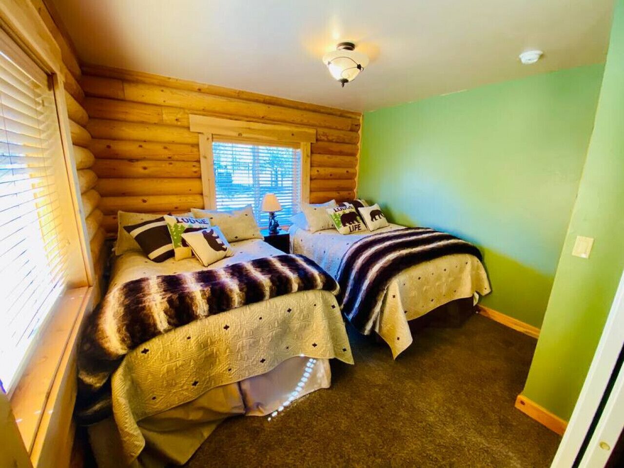 Una habitación acogedora con dos camas, una ventana con persianas y una pared verde.