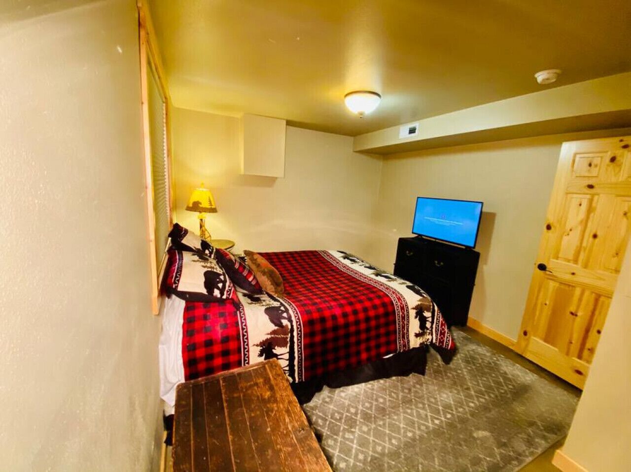 Ein Schlafzimmer mit einem Bett, einer hölzernen Bank, einem Fernseher und einer Holztür.