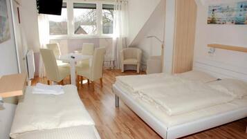 Ein Zimmer mit zwei Betten, einem Esstisch und Stühlen.