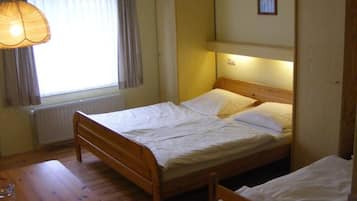A single bed with a wooden frame, a bedside table, and a hanging lamp.