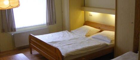 Una cama individual con cabecera de madera, una mesita de noche y una lámpara colgante.