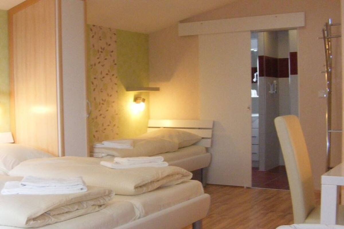 Ein Hotelzimmer mit zwei Betten, einer Sitzecke und einem durch eine offene Tür einsehbaren Badezimmer.