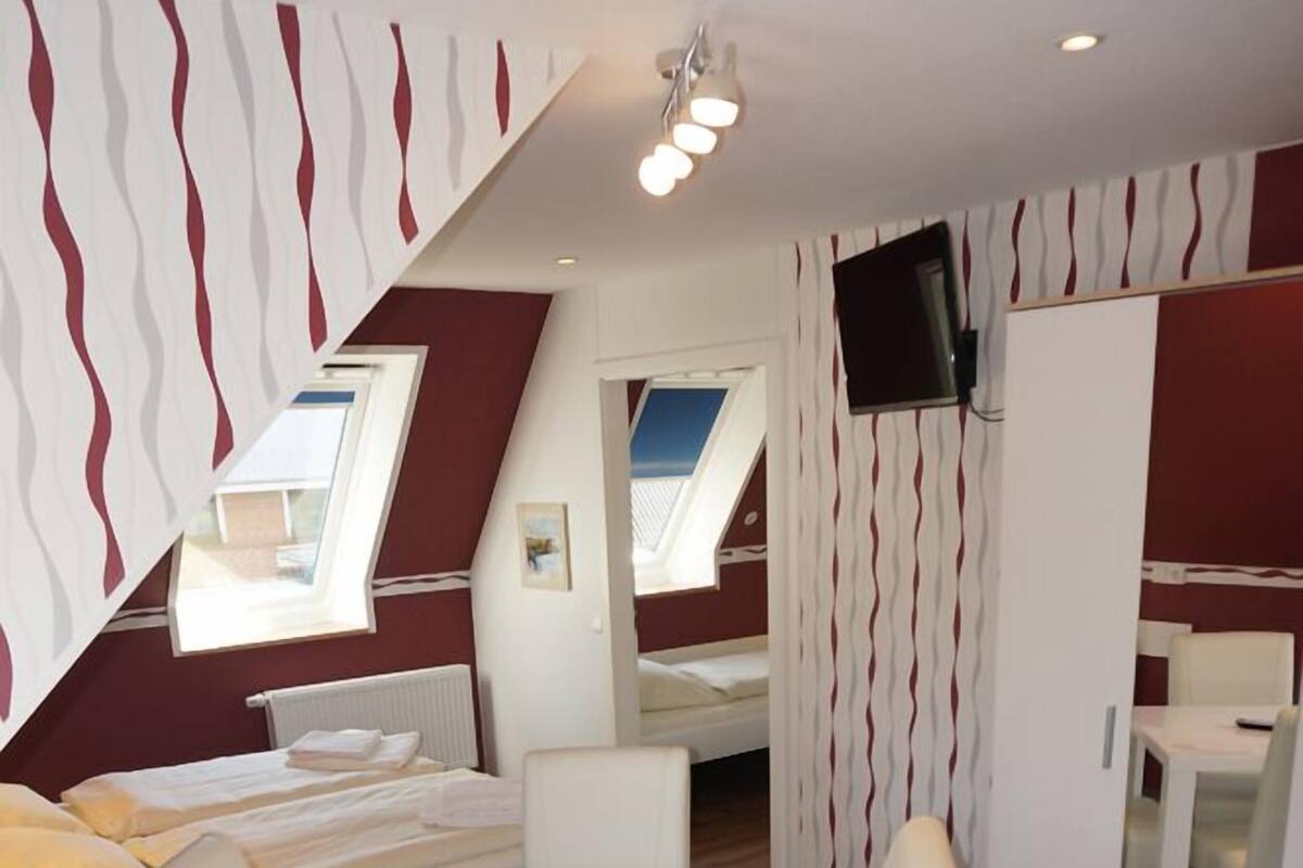 Ein modernes Hotelzimmer mit Bett, Esstisch und Fernseher.
