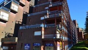 A multi-story building with balconies and signage for "Les Belles Challes" and "LES ARCS AGENCY".