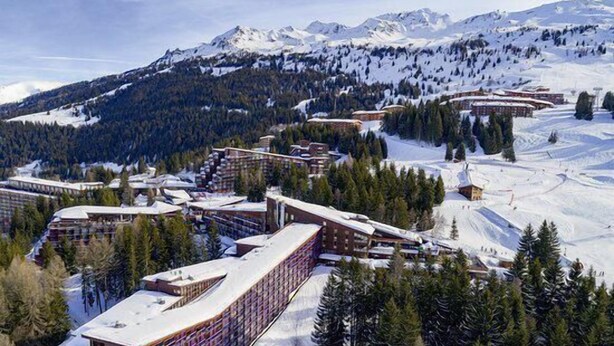 A ski resort with multiple buildings, including a large hotel with a curved facade and a smaller lodge.