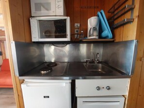 A compact kitchenette with a microwave, coffee maker, and a small refrigerator.