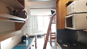 A compact kitchen with a microwave, stove, and a small dining area.