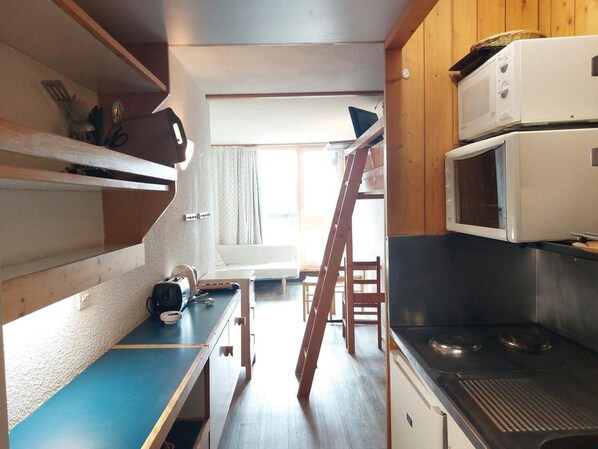 A compact kitchen with a microwave, stove, and a small dining area.