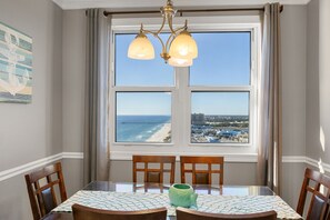 Enjoy a meal with a view of the beach and pier from this dining area, featuring a table, chairs, and a beautiful chandelier.
