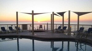 Zona de piscina con sillones de descanso y vistas al atardecer sobre el agua.