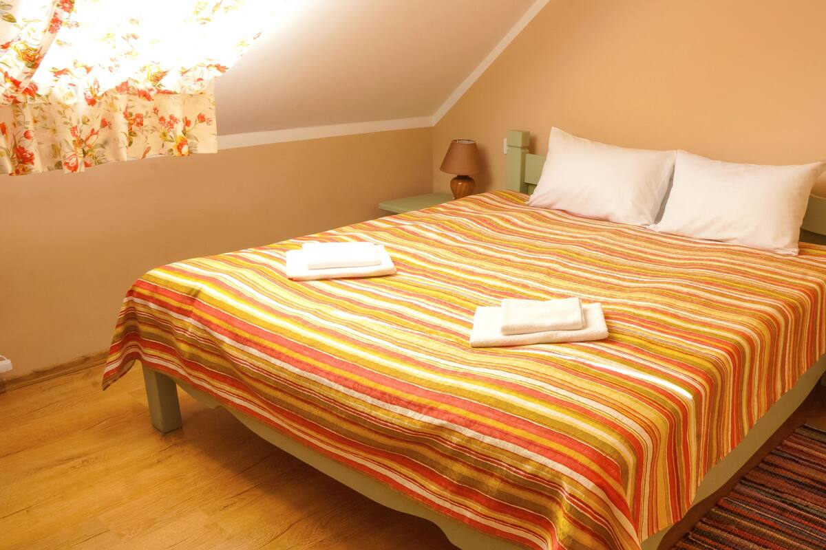 A hotel room with a bed, two bedside tables, a lamp, and a window with curtains.