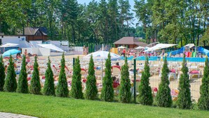 A campground with tents, a swimming pool, and a fenced area with trees.