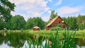 A rustic cabin by a lake with a clear view of the surrounding forest.