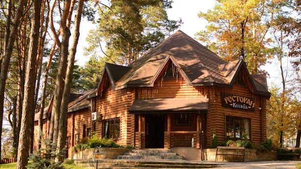 A log cabin-style building with a steeply pitched roof, a front porch with steps, and a sign that reads "RECTORAH."