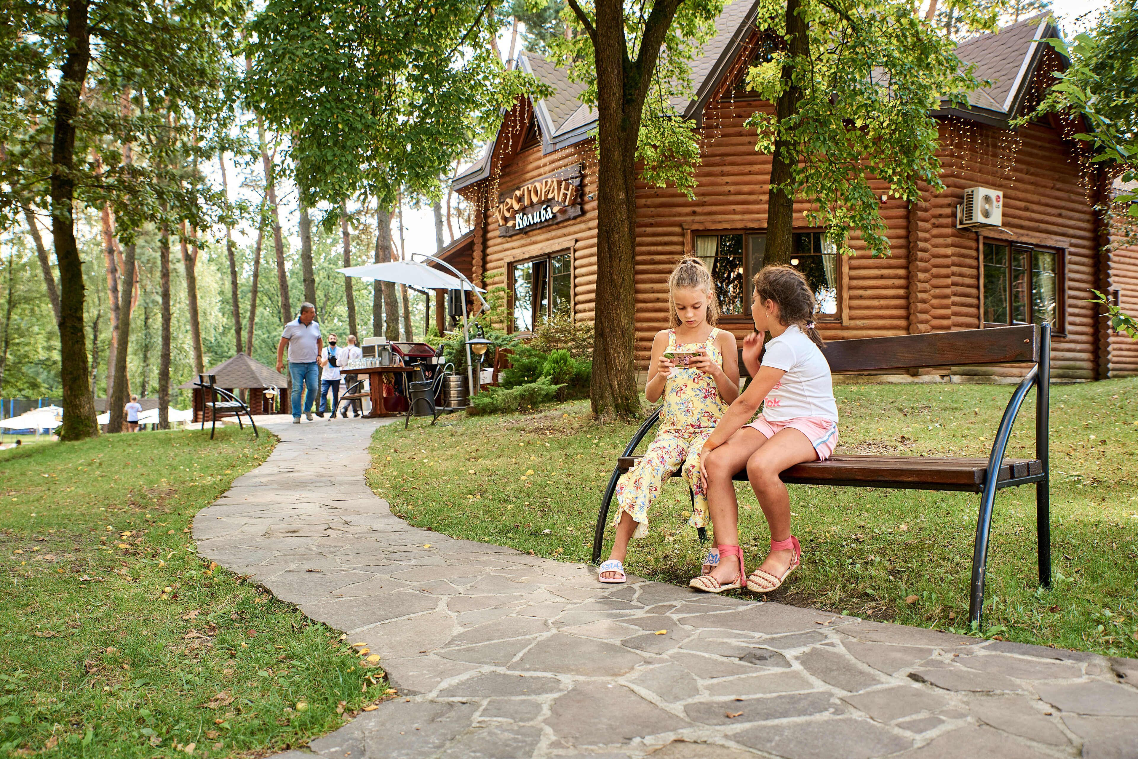 A wooden cabin with a stone pathway leading to a bench.