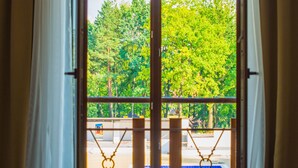 A room with a large sliding glass door leading to a balcony with a pool view.
